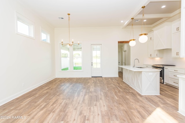 kitchen featuring pendant lighting, stainless steel range with gas cooktop, sink, and a kitchen island with sink