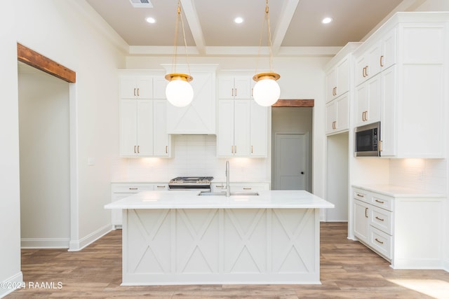 kitchen featuring white cabinetry, a kitchen island with sink, sink, and decorative light fixtures