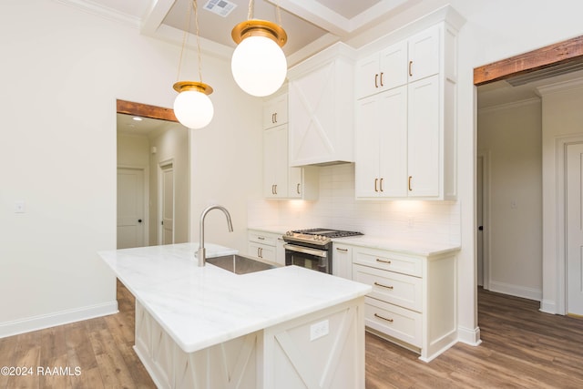 kitchen featuring a center island with sink, sink, hanging light fixtures, gas range, and white cabinetry