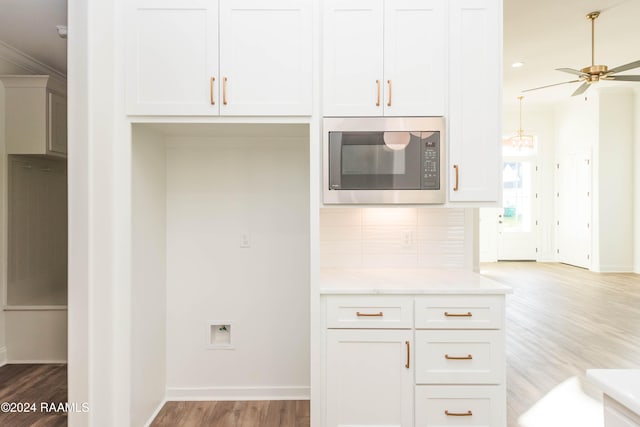 kitchen with backsplash, light hardwood / wood-style flooring, ceiling fan, built in microwave, and white cabinetry