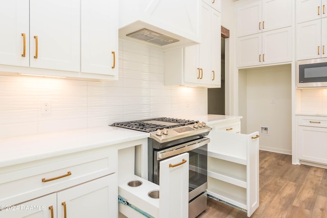 kitchen featuring white cabinets, stainless steel appliances, light hardwood / wood-style flooring, and premium range hood