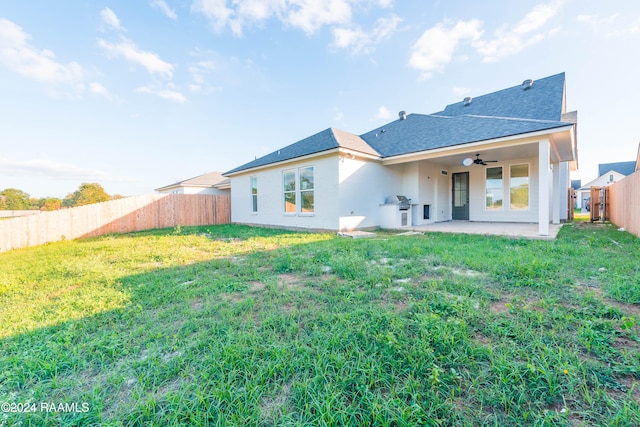 rear view of house with a patio, ceiling fan, and a lawn