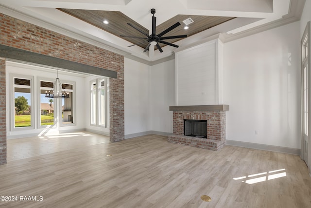 unfurnished living room with light hardwood / wood-style flooring, ornamental molding, ceiling fan with notable chandelier, and a fireplace