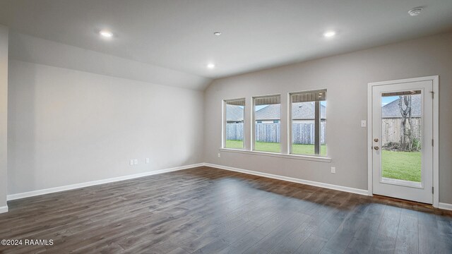 spare room featuring dark wood-type flooring, lofted ceiling, and a healthy amount of sunlight