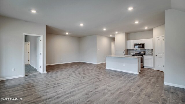 kitchen featuring white cabinets, sink, a center island with sink, stainless steel appliances, and light wood-type flooring