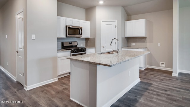 kitchen with white cabinets, a center island with sink, appliances with stainless steel finishes, and tasteful backsplash