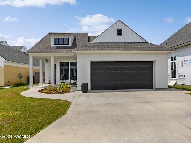 view of front of property with covered porch, a garage, and a front lawn