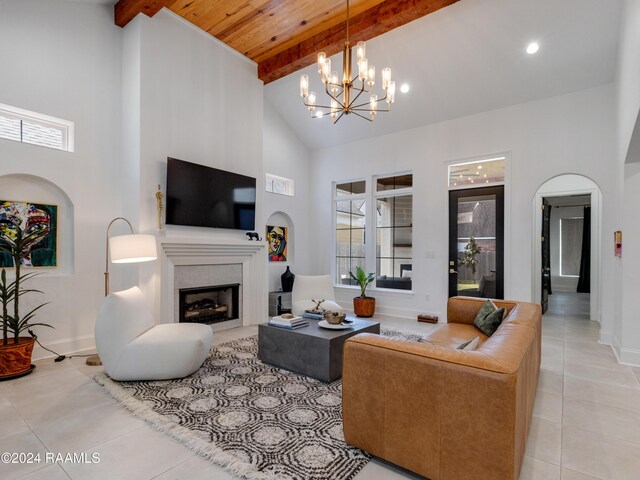 tiled living room with high vaulted ceiling, a tiled fireplace, wooden ceiling, a notable chandelier, and beamed ceiling