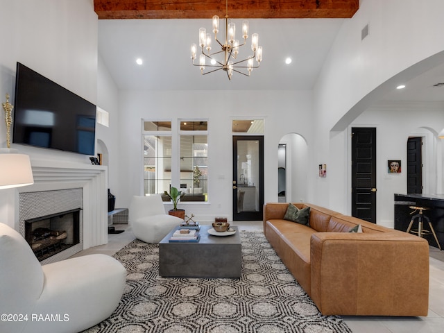 tiled living room with beam ceiling, high vaulted ceiling, a tiled fireplace, and an inviting chandelier