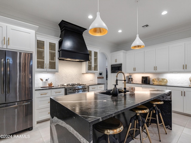 kitchen with custom range hood, stainless steel appliances, a kitchen island with sink, and decorative backsplash