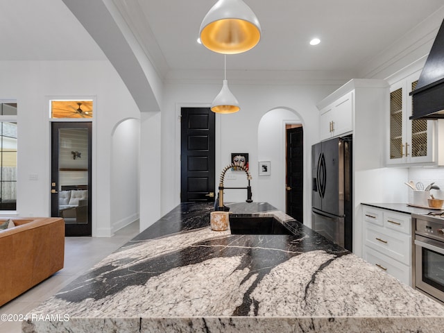 kitchen featuring sink, dark stone countertops, ornamental molding, decorative light fixtures, and stainless steel appliances