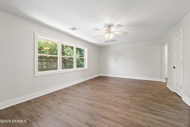 spare room featuring ceiling fan, wood finished floors, visible vents, and baseboards