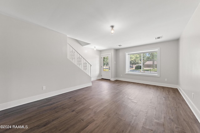 unfurnished living room featuring visible vents, baseboards, dark wood finished floors, and stairway