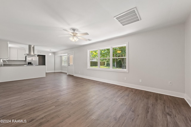 unfurnished living room featuring dark wood-style floors, visible vents, baseboards, and ceiling fan