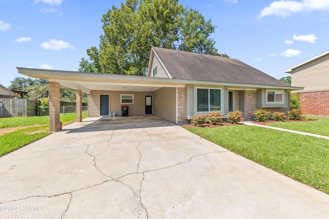 view of front facade with driveway, brick siding, a front yard, and fence