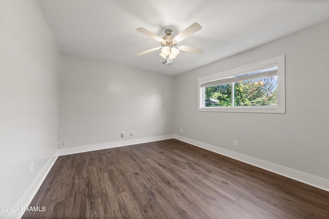 spare room with baseboards, a ceiling fan, and dark wood-style flooring