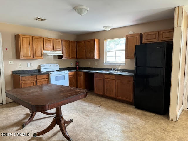 kitchen featuring sink, black refrigerator, light tile patterned flooring, and white range with electric stovetop