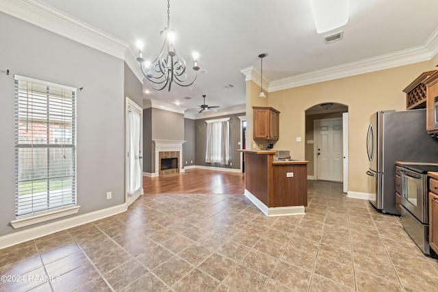 kitchen featuring ceiling fan with notable chandelier, a tiled fireplace, hanging light fixtures, stainless steel appliances, and crown molding