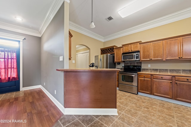 kitchen with decorative light fixtures, stainless steel appliances, light wood-type flooring, and crown molding