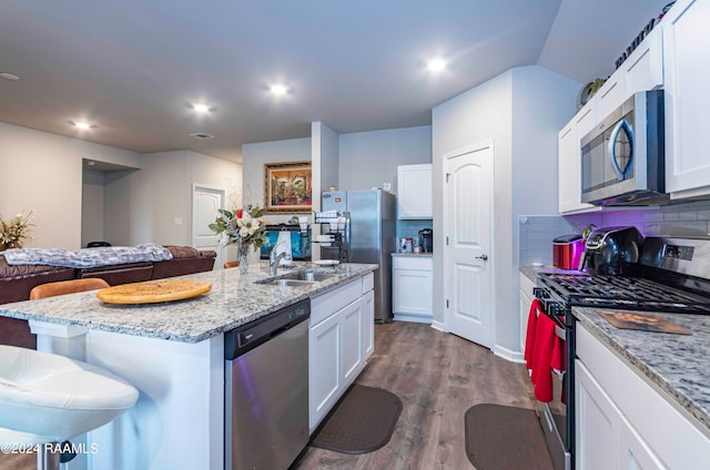 kitchen featuring white cabinetry, a center island with sink, appliances with stainless steel finishes, and backsplash