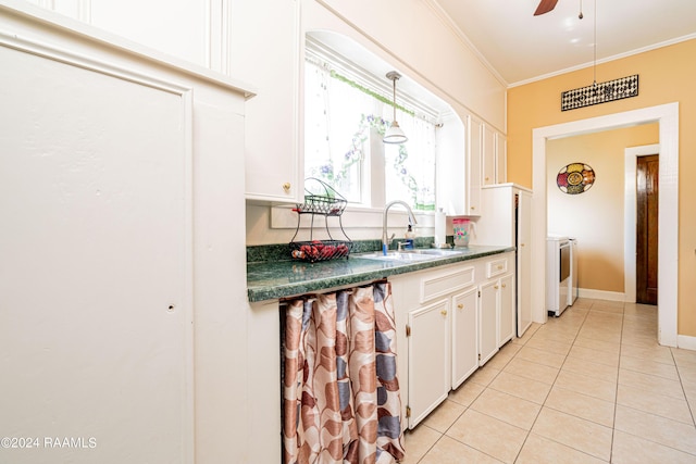 kitchen featuring a sink, dark countertops, separate washer and dryer, crown molding, and light tile patterned floors
