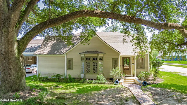 view of front of house featuring a shingled roof and a front lawn