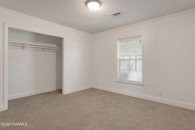 unfurnished bedroom with light carpet, a closet, and crown molding