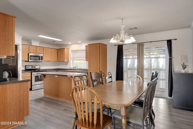 dining space with crown molding, a notable chandelier, and light wood-type flooring