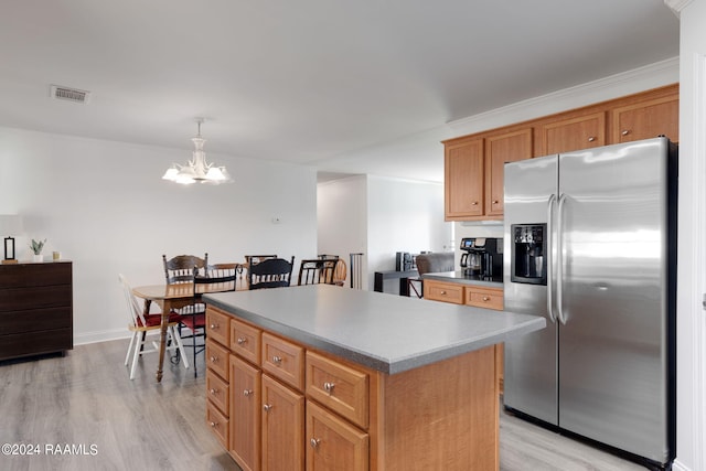 kitchen featuring stainless steel fridge, light wood-type flooring, crown molding, decorative light fixtures, and a center island