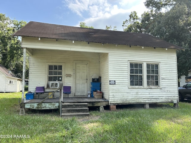 view of front of home with a porch, a front yard, and roof with shingles