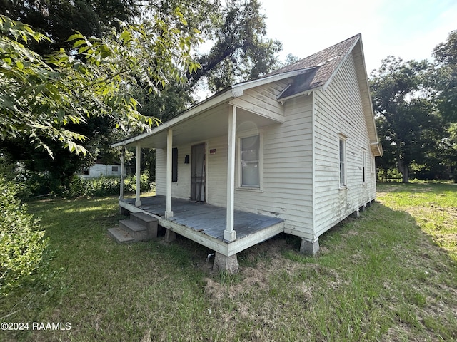 exterior space featuring a porch, a yard, and a shingled roof