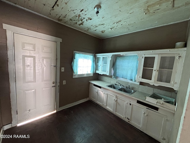 kitchen featuring a sink, baseboards, white cabinets, light countertops, and dark wood-style floors