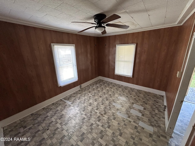 unfurnished room with wooden walls, baseboards, and crown molding