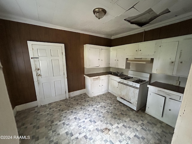 kitchen with range hood, white gas range, ornamental molding, white cabinets, and wood walls