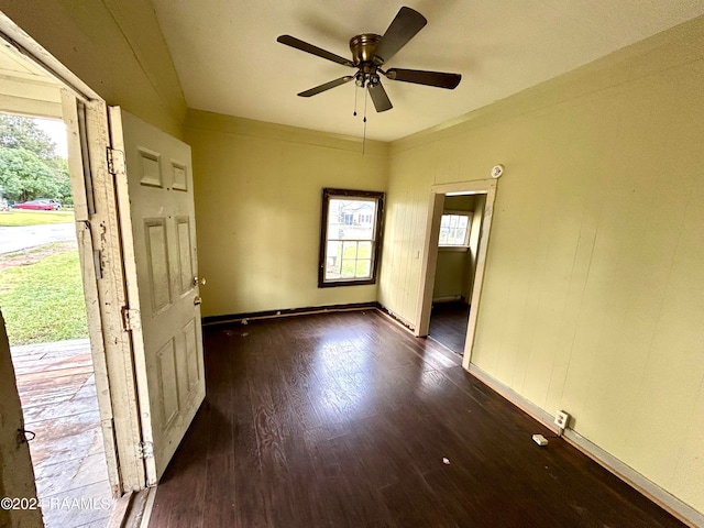 empty room with dark wood-style flooring, ceiling fan, and baseboards