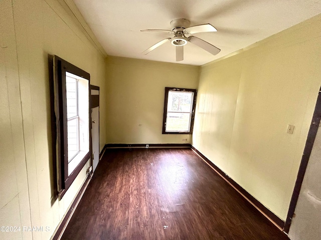 empty room with dark wood-style floors, baseboards, and a ceiling fan