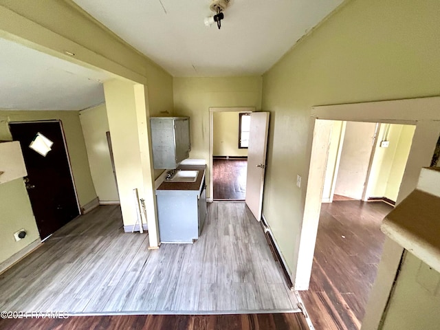 kitchen with a sink, baseboards, and wood finished floors