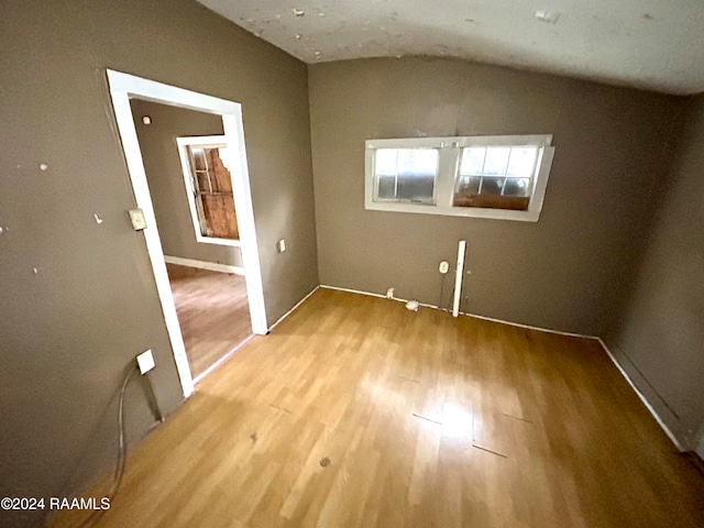 unfurnished room featuring lofted ceiling and wood finished floors