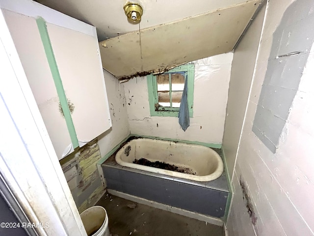 bathroom with concrete block wall and a tub