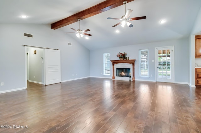 unfurnished living room featuring beam ceiling, a barn door, dark wood-type flooring, and high vaulted ceiling