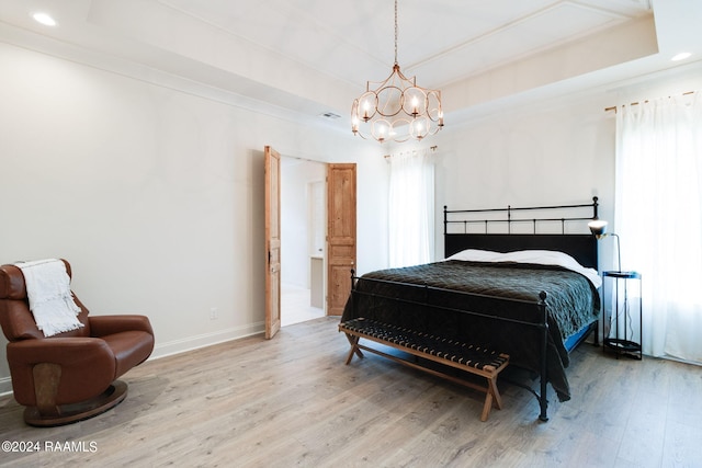 bedroom featuring a raised ceiling, hardwood / wood-style floors, and a chandelier