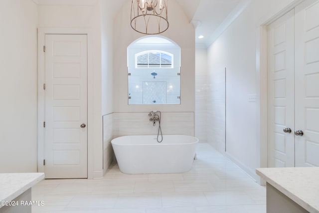 bathroom with ornamental molding, vanity, tile patterned floors, tile walls, and a bathtub