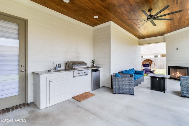 view of patio with an outdoor living space, ceiling fan, an outdoor kitchen, and area for grilling