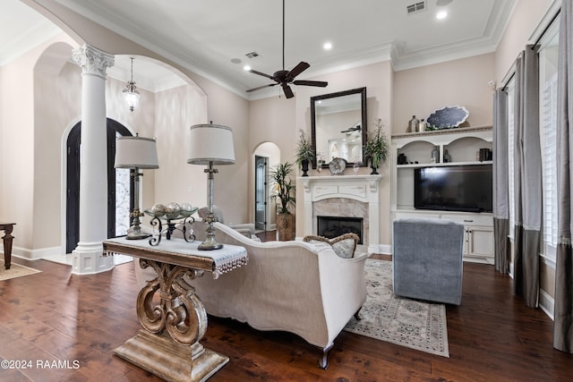 living room featuring ornate columns, ornamental molding, hardwood / wood-style flooring, ceiling fan, and a premium fireplace