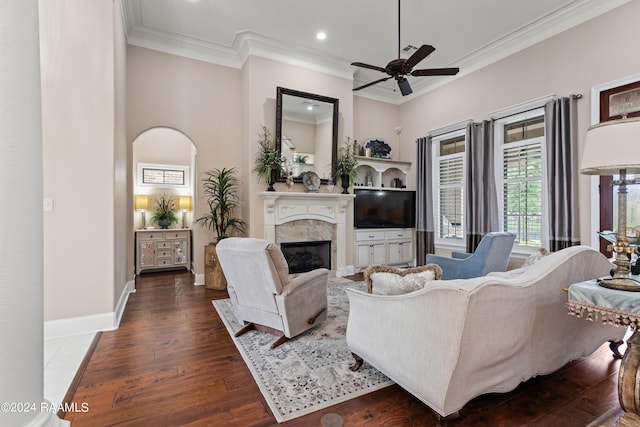 living room featuring a high ceiling, a fireplace, dark wood-type flooring, ceiling fan, and crown molding