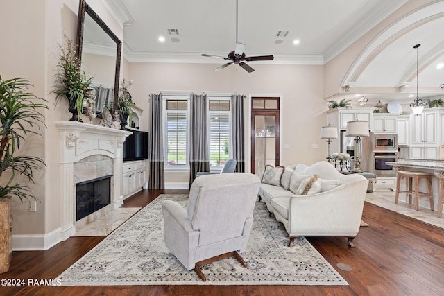 living room with ceiling fan, a high end fireplace, hardwood / wood-style floors, and ornamental molding