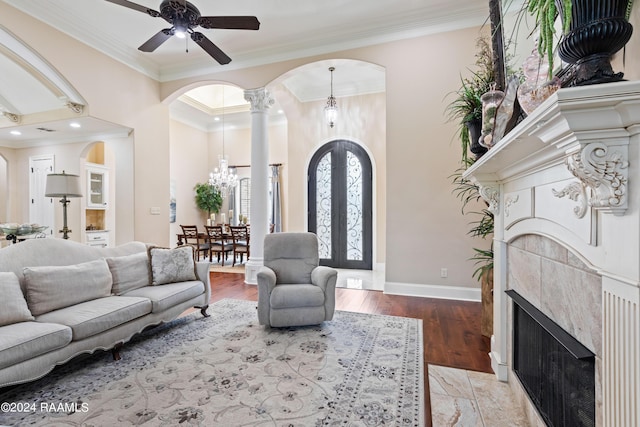 living room with baseboards, arched walkways, ornamental molding, french doors, and light wood-style floors