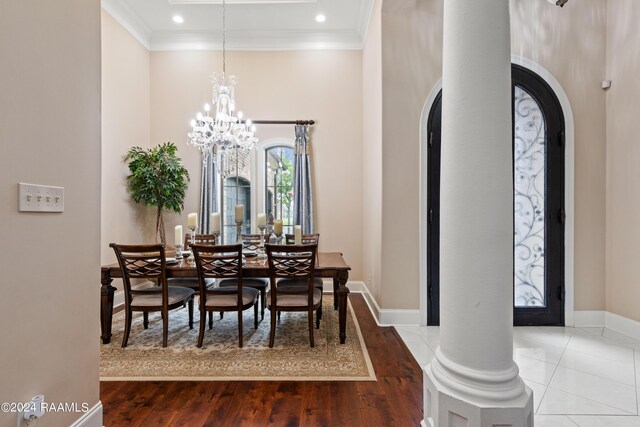 dining area featuring ornate columns, hardwood / wood-style flooring, crown molding, and a chandelier