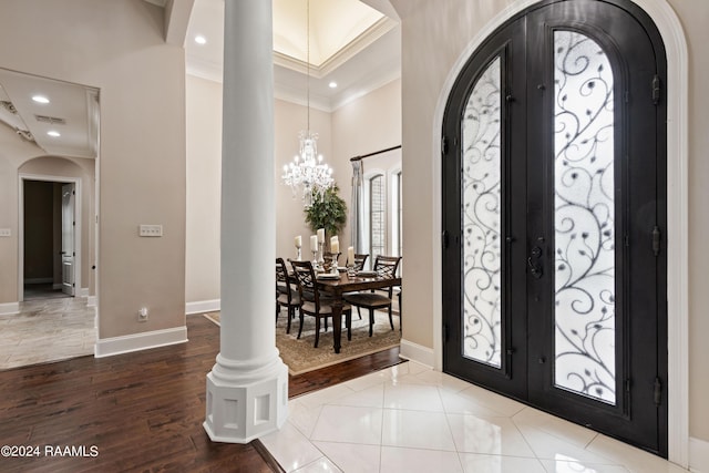 foyer featuring an inviting chandelier, arched walkways, crown molding, and french doors