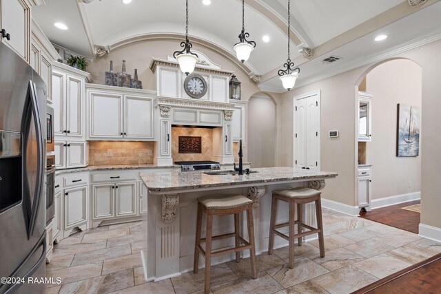 kitchen featuring stainless steel appliances, tasteful backsplash, sink, a center island with sink, and light wood-type flooring